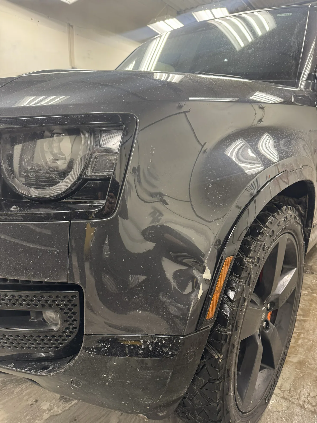 Black Land Rover Defender front fender marked for dent repair