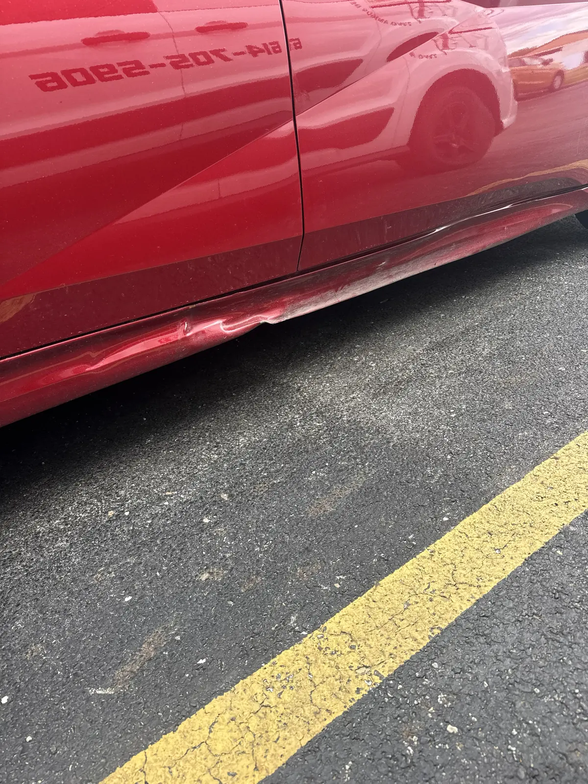 Red sedan rocker panel crease before repair