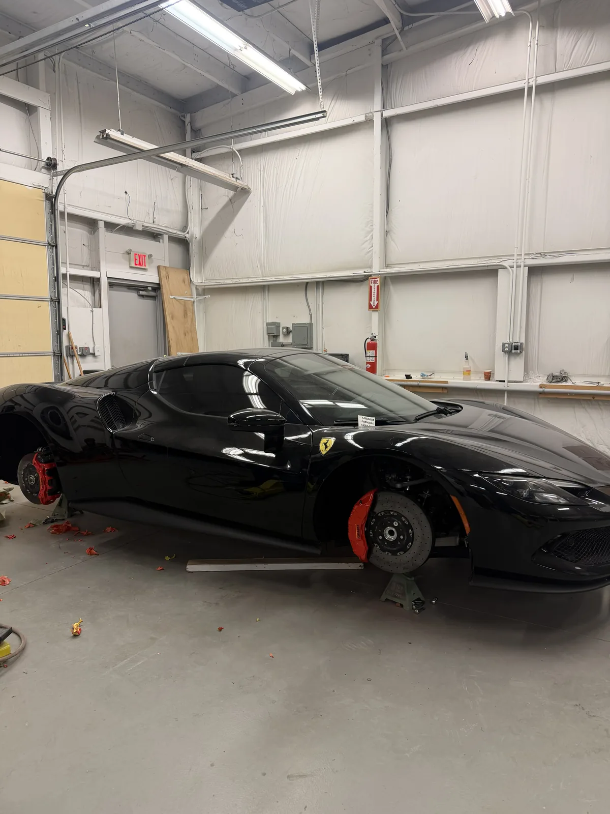 Black Ferrari 296 on stands inside the shop with wheels off